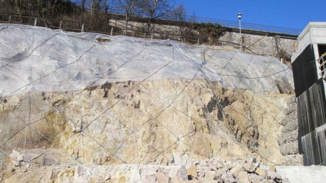 Absicherung der Felsböschungen bergseitig von Baustellenflächen mittels Metallgitternetzen, verstärkt mit Stahlseilen. Wohnbauzone Huberweide, Ritten (BZ), 2019. Absicherung der Felsböschungen bergseitig von Baustellenflächen mittels Metallgitternetzen, verstärkt mit Stahlseilen. Wohnbauzone Huberweide, Ritten (BZ), 2019.