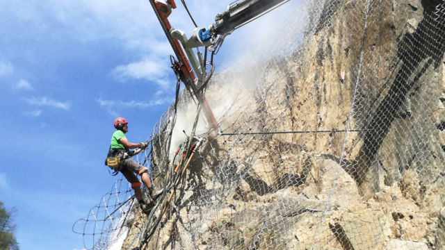 Messa in sicurezza di pareti rocciose tramite rete zincata e pannelli in funi di acciaio: Esecuzione dei fori per gli ancoraggi in roccia tramite perforatrice montata sulla gru´, Vadena (BZ), 2017. Messa in sicurezza di pareti rocciose tramite rete zincata e pannelli in funi di acciaio: Esecuzione dei fori per gli ancoraggi in roccia tramite perforatrice montata sulla gru´, Vadena (BZ), 2017.